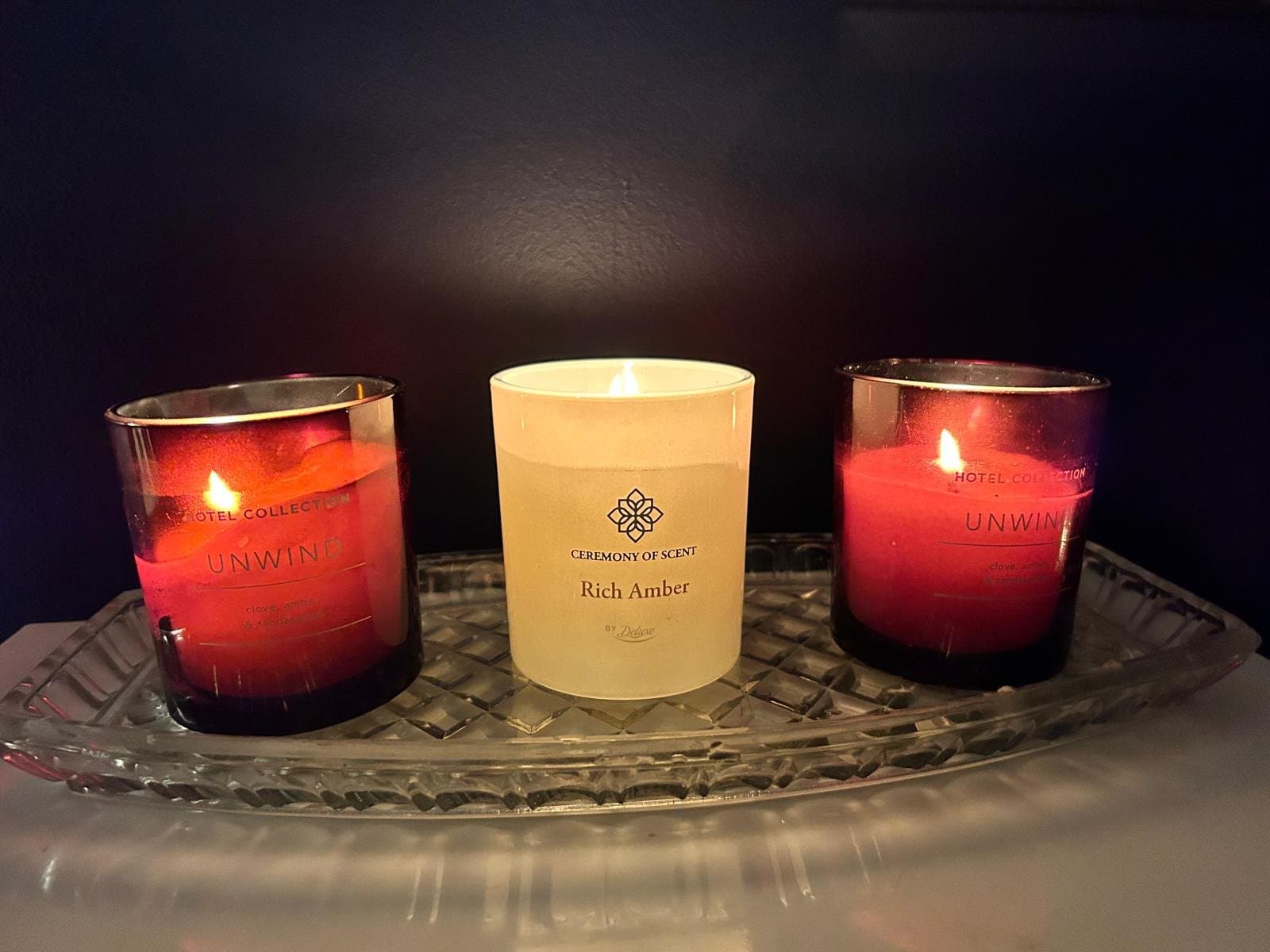 Three candles glowing on a wooden shelf in the treatment room