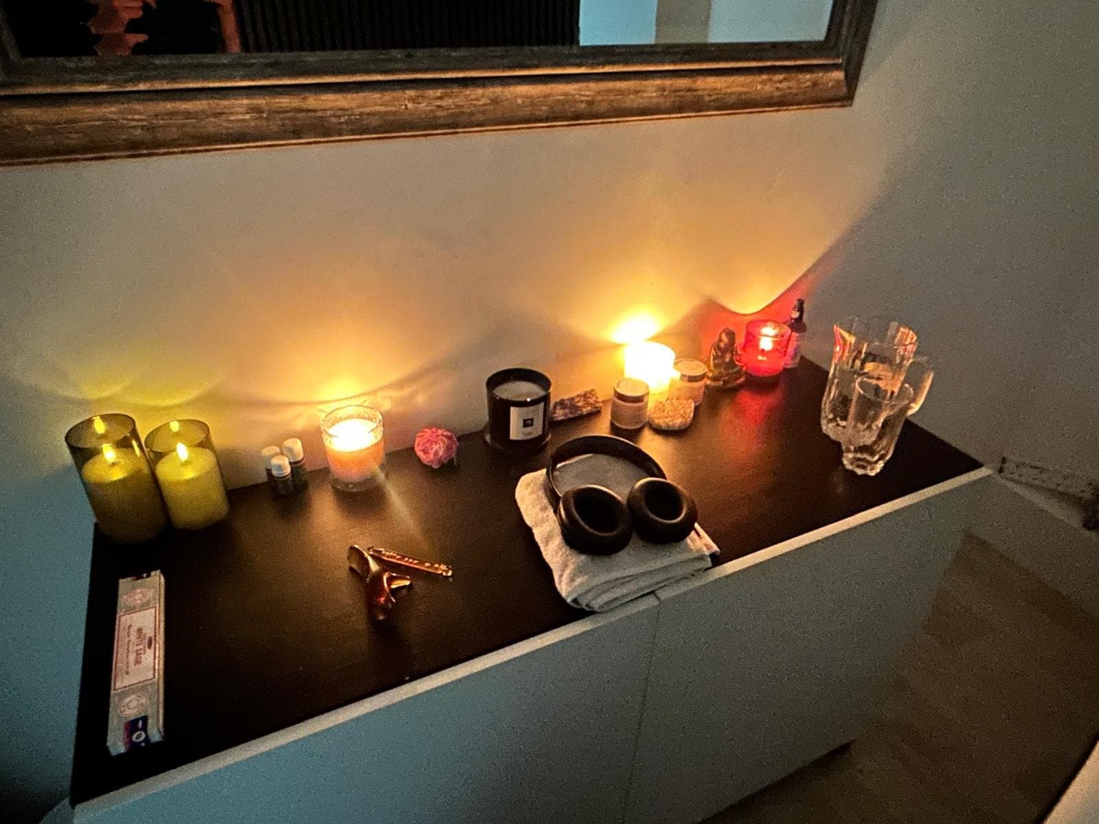 Warmly lit shelf with candles, oils and crystals