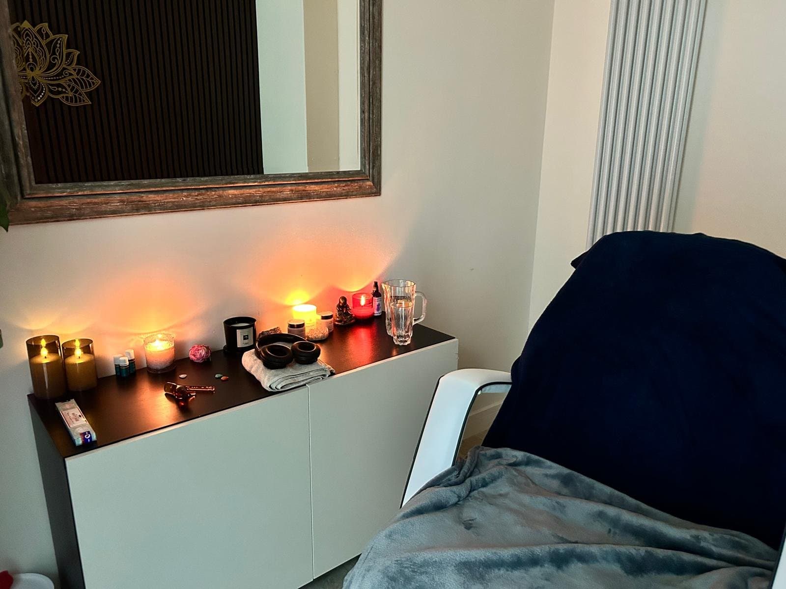 The Aruna Holistics treatment room, with candles lit beneath a lotus mirror and a blanket laid over the treatment chair